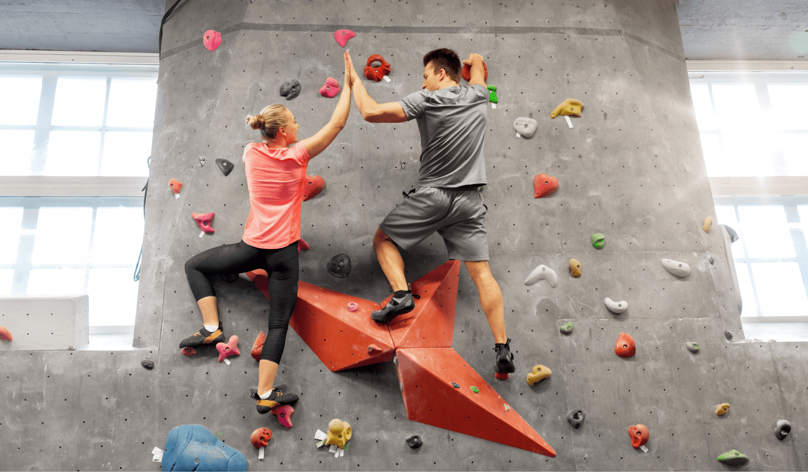 two people scaling a bouldering wall in a climbing gym