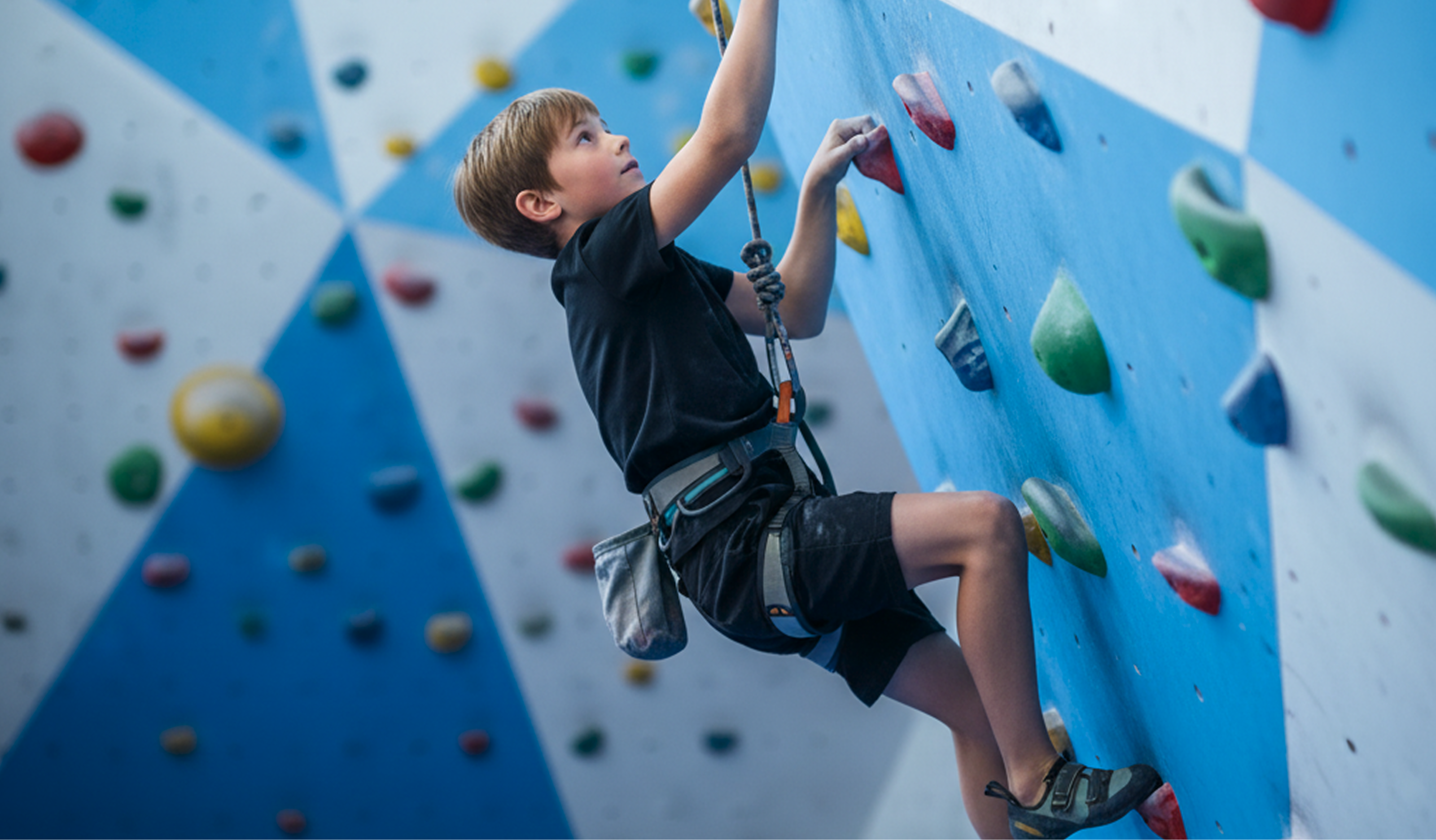 A young boy climbing up a wall in a rock climbing gym